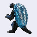 A small monster figurine resembling a turtle-like creature with a glossy blue shell and black body, shown against a plain light gray background.