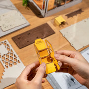 In progress shot of the Holiday Garden House diorama being assembled, with a shelf being pieced together out of wooden cut out pieces.