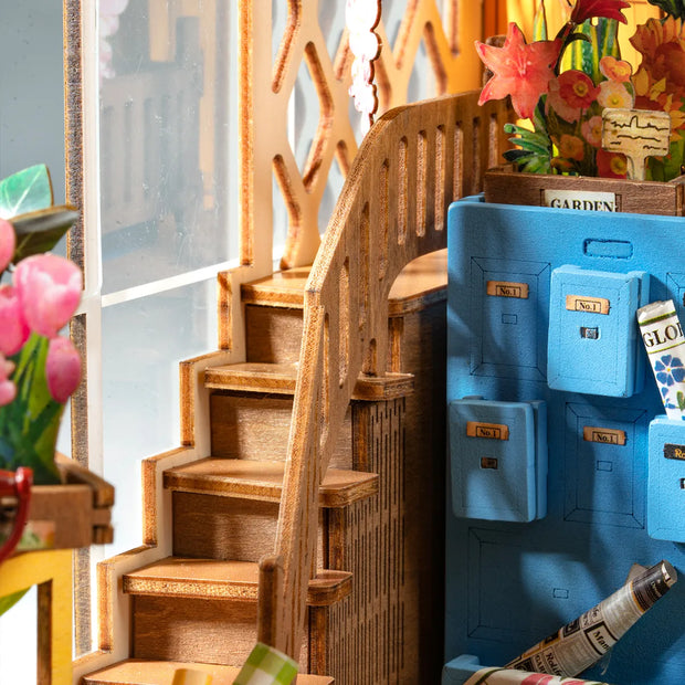 Detail shot of Holiday Garden House bookend diorama, featuring a set of wooden steps next to a file cabinet with certain drawers jutted out. 