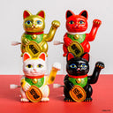 Four colorful cat figurines with raised paws on a red and white background
