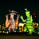 Two colorful kaiju monster-like sculptures against a cityscape at night.