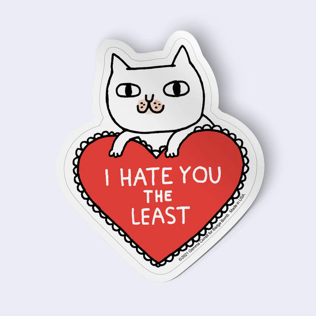Sticker with a cat holding a heart that says 'I Hate You The Least' on a light gray background