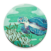 Painting on circular panel of a sea turtle, swimming in sea foam green water with kelp reaching up towards it. Background has subtle abstract designs.
