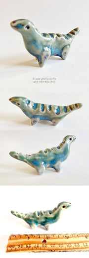 Small ceramic sculpture of a bluish green dinosaur, with ridges along its back and a long neck.