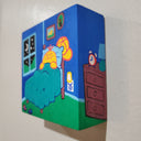 Painting held in the hand of the artist of a yellow cartoon character laying in a bed in a children's room. It has framed photos on the wall, small toy cars and a night sky visible from a nearby window. Shown at side angle.