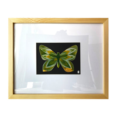 Illustration on cut out paper of a butterfly with gold and deep green wings, with abstract wing patterns akin to pointed leaves. Butterfly is mounted on black paper and in a light grain wooden frame with a white mat.