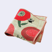 Greenish beige square handkerchief with a small black bumblebee flying over large rounded red and green flowers. Folded.
