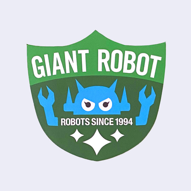 Die cut green sticker of a 3 point shield, that reads "giant robot" across the top and features a blue robot above text that reads "robots since 1994"