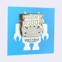 A square enamel pin featuring a stylized robot with bold font that reads "Giant Robot" in a style akin to metal band logos, on a light gray background.