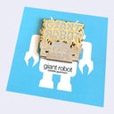 A square enamel pin featuring a stylized robot with bold font that reads "Giant Robot" in a style akin to metal band logos, on a light gray background.