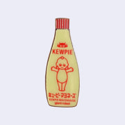 Die cut enamel pin of a bottle of Kewpie brand mayonnaise, with an added "giant robot" written small along the bottom.