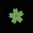 Die cut enamel pin of a stylized cherry blossom, with slightly pointed geometric petals and a white line art center. Pin is glowing in the dark.