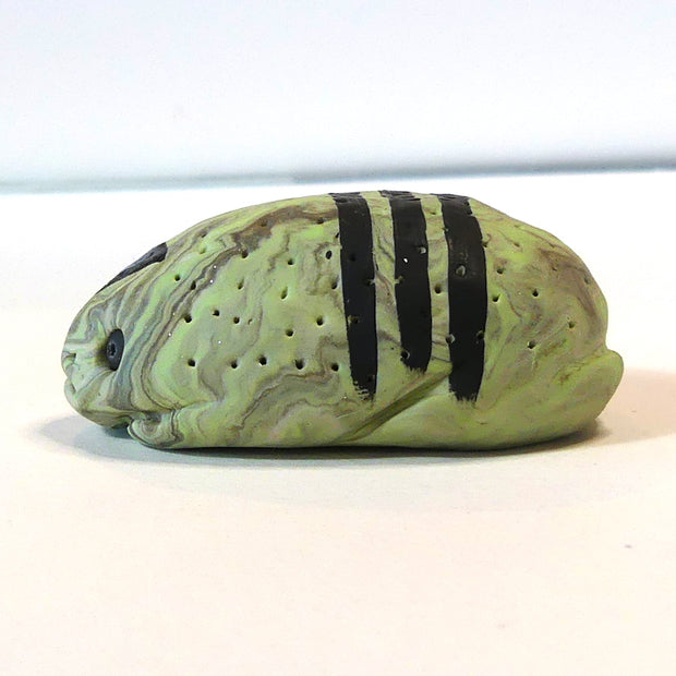 Small marbled green clay sculpture of a frog with a very pudgy body and a black triangle on its forehead. It sits with its arms and legs pulled in.
