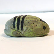 Small marbled green clay sculpture of a frog with a very pudgy body and a black triangle on its forehead. It sits with its arms and legs pulled in.