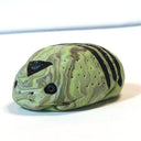 Small marbled green clay sculpture of a frog with a very pudgy body and a black triangle on its forehead. It sits with its arms and legs pulled in.