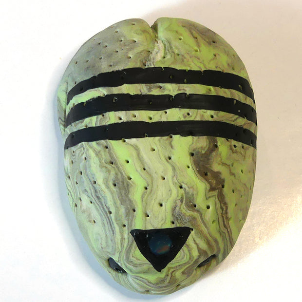 Small marbled green clay sculpture of a frog with a very pudgy body and a black triangle on its forehead. It sits with its arms and legs pulled in.