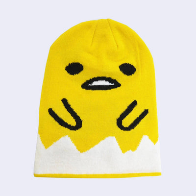 Yellow beanie featuring a large graphic of Gudetama, as if his body is the beanie itself. His face has an open mouth gape and his arms come inwards. Around him is a cracked white egg shell look.