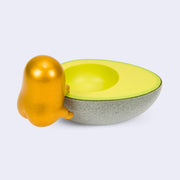 Back view of Gudetama figure, metallic gold and climbing up into a half of an avocado. Its butt cheeks are pronounced. 