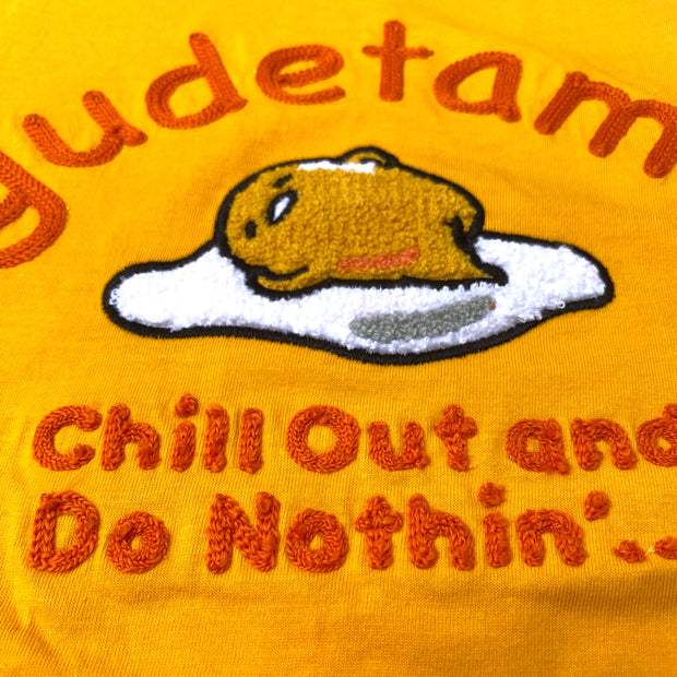 Close up showing texture of  tufted embroidery of Sanrio's Gudetama, laying on his egg white. Above him reads "gudetama" and below "chill out and do nothin'..."