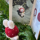 Crocheted bunny with a strawberry hat looking at an open page spread of the Gumi Buni zine.