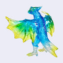 A translucent dragon figurine or ornament in shades of blue, green, and yellow, shown against a plain light gray background.