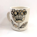 White ceramic mug with black floral design on a white background
