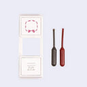 Two small ink refill pods, one black and one red, with decorative designs on a light purple background.