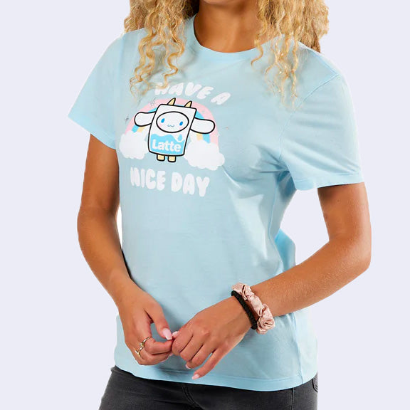 Light blue t-shirt with a graphic of Sanrio's Cinnamoroll, dressed as a carton of milk and standing in front of a pastel rainbow with text that reads "Have a Nice Day"