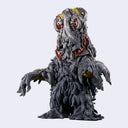A detailed collectible figure of a monstrous, smog creature with a melting black body, 2 red glowing eyes, yellow accents, and outstretched arms.