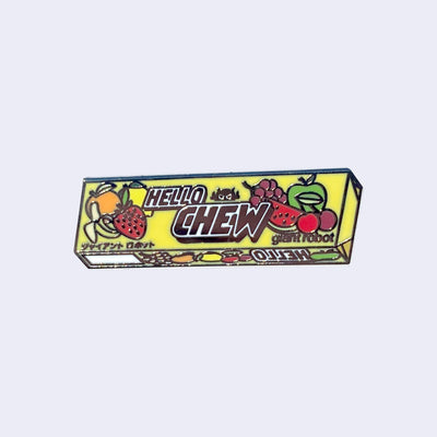 Die cut enamel pin of a sleeve of Hi-Chew candy in yellow product packaging, with the design slightly edited. The front says "Hello Chew" and has a small graphic of a robot head, along with "giant robot" written in lowercase in bottom right corner.