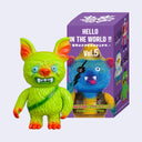 Colorful toy figure next to its packaging box on a white background