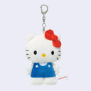 Plush keychain of Hello Kitty with a red bow and blue dress on a light gray background