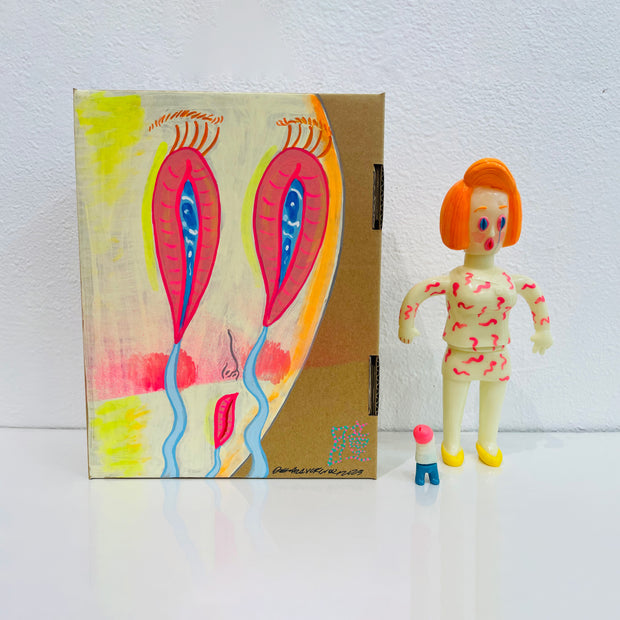 Light yellow soft vinyl figure of a woman dressed in business attire, with styled orange hair and an expressive crying cartoon face. It stands next to a painted box.
