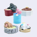 Set of small animal figurines in various states of relaxation in different shaped baths or tubs.