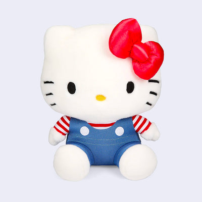 Plush doll of Hello Kitty, wearing blue overalls with a red and white striped shirt underneath. She has her iconic red bow. Her head is larger than her body.
