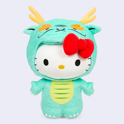 Plush doll of Hello Kitty, dressed up in a mint green dragon suit with a hood around her head. She has her iconic red bow coming out of the costume.