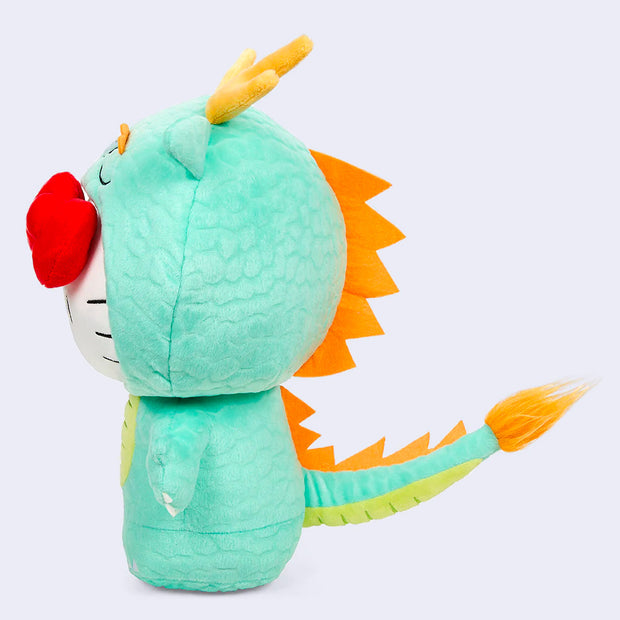 Plush doll of Hello Kitty, dressed up in a mint green dragon suit with a hood around her head. She has her iconic red bow coming out of the costume.