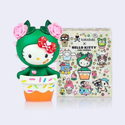 Vinyl figure of Hello Kitty dressed as a cactus, with the lower half of her body in a pot coated in frosting and sprinkles. She stands next to her product packaging.