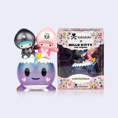 Vinyl figure of Sanrio's Little Twin Stars, a pink haired girl and a blue haired boy, riding atop of a smiling purple narwhal. They stand next to its product packaging.