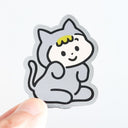 Sticker of a child in a cat costume held by a hand on a white background