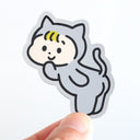 Sticker of a cartoon kid in a silver cat costume with hair held by a hand on a white background