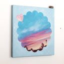 Painting on canvas of a sunset time with a silhouette of the tops of roofs and trees at the bottom. The scene is enclosed in a scalloped border with blue polkadots. 