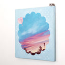 Painting on canvas of a sunset time with a silhouette of the tops of roofs and trees at the bottom. The scene is enclosed in a scalloped border with blue polkadots. 