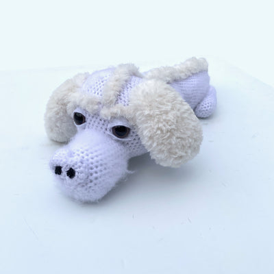 Crocheted sculpture of Falkor from The Neverending Story, with a crocheted body and fluffy ears and back lining.