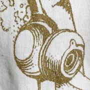 White shirt with a line art illustration in the center of a woman with many mechanical head and body elements. Line art is in a dark gold color. Close up.