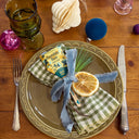 Decorative table setting with a plate, napkin, and lemon slice on a wooden table.