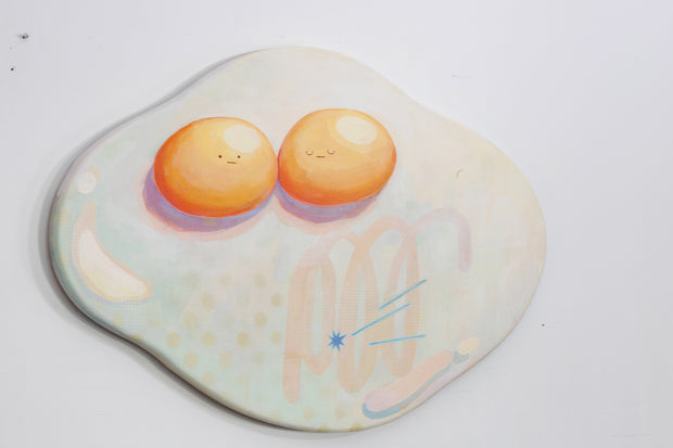 Die cut canvas of a pair of 2 eggs sharing a single egg white. The yolks are touching and have small faces. The egg white contains a subtle polka dot and scribble design.