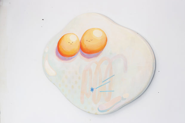 Die cut canvas of a pair of 2 eggs sharing a single egg white. The yolks are touching and have small faces. The egg white contains a subtle polka dot and scribble design.