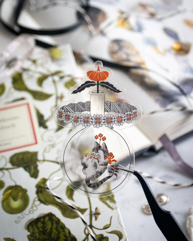 Clear sticker of a cat in a jar with flowers coming up atop.