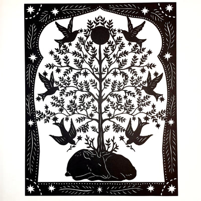 Black paper cutting art of a deer, curled into itself and sleeping. A large tree grows atop of it, with many birds taking star shaped blossoms off the tree. Piece is framed wtih intricate cut paper border.